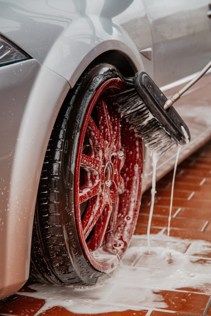 Sølvfarget bil med røde felger vaskes